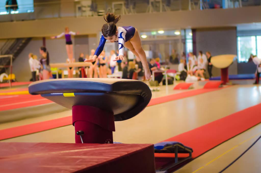Young gymnast girl performing jump on a vault while practicing for the competition